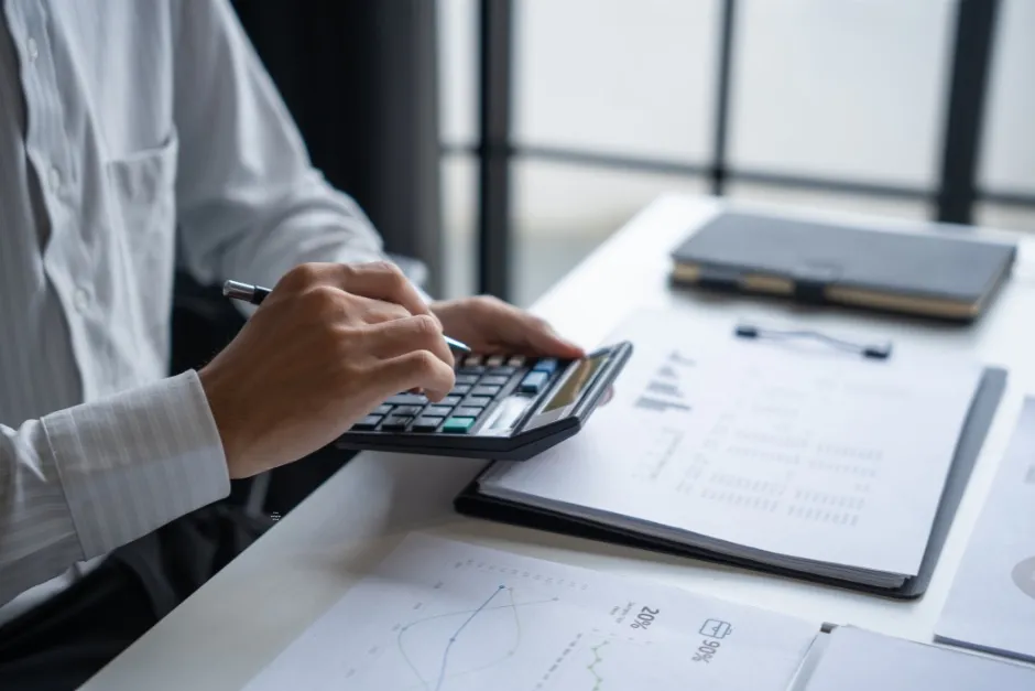 Working through valuation figures on a calculator alongside printed financial reports