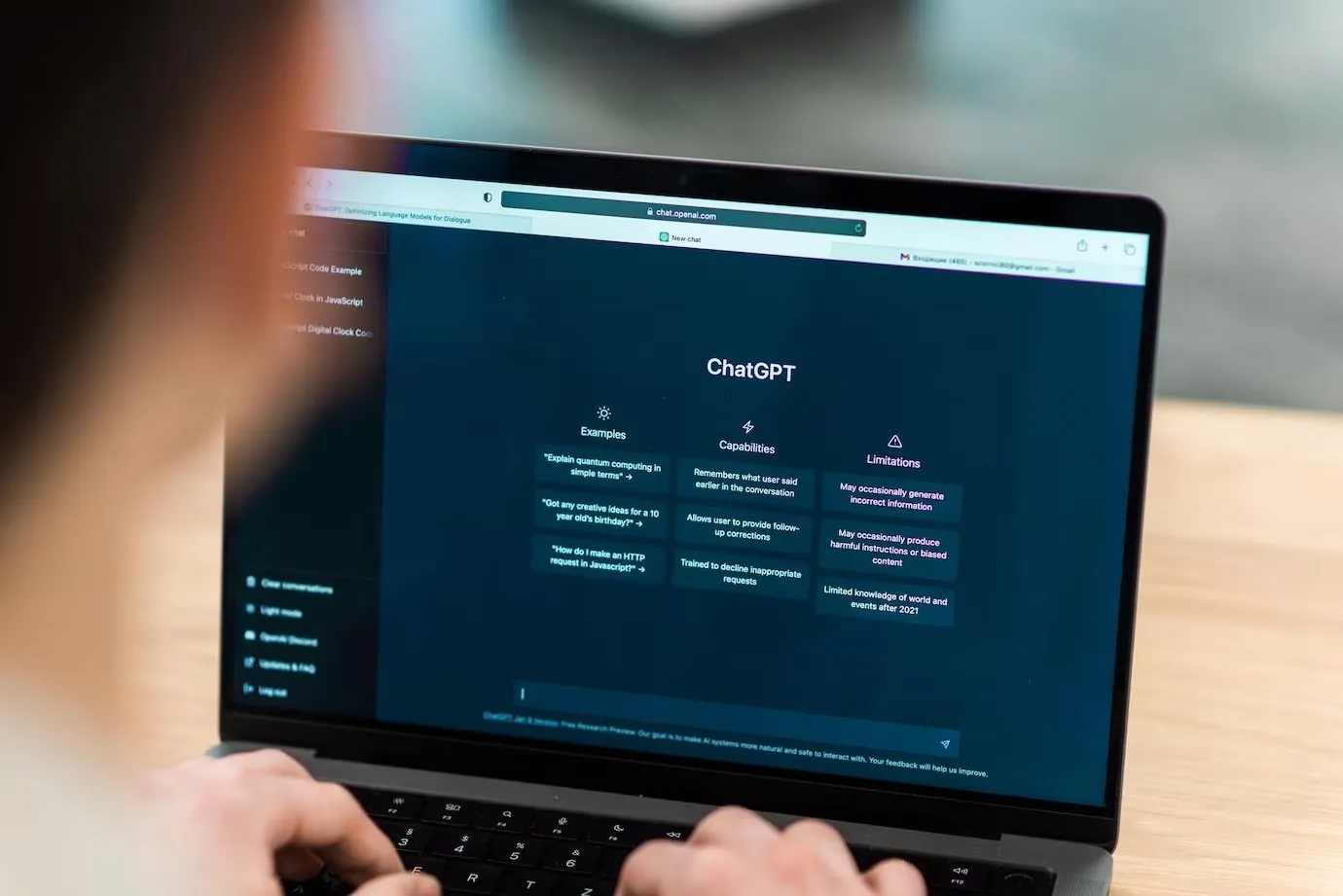 A laptop showing the ChatGPT interface with columns for examples, capabilities and limitations