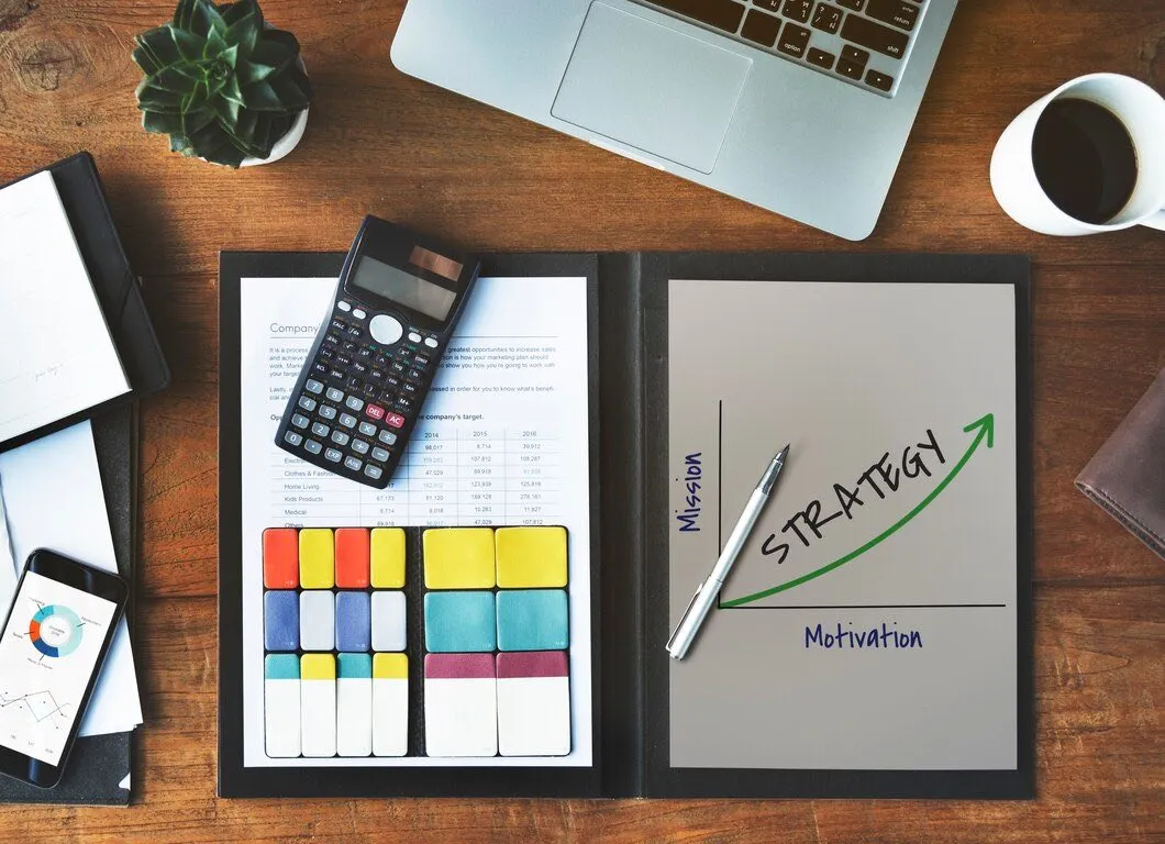 A desk with a calculator, colour-coded notes and a hand-drawn strategy graph