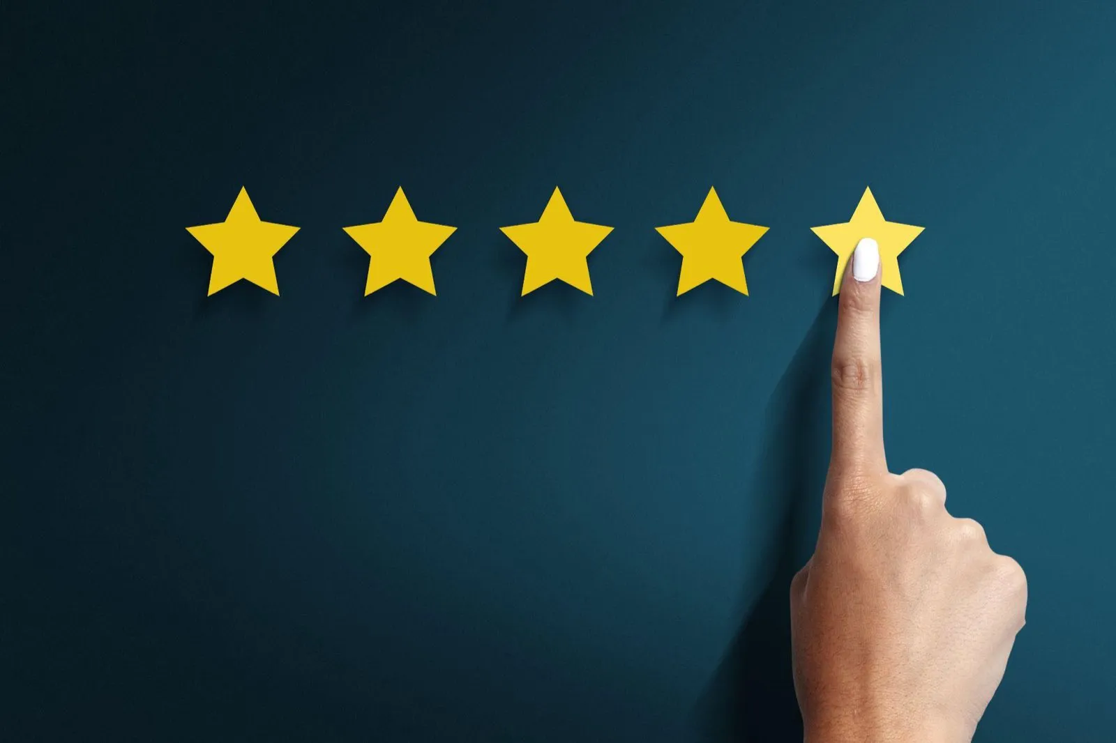 A hand touching the fifth of five gold stars in a rating
