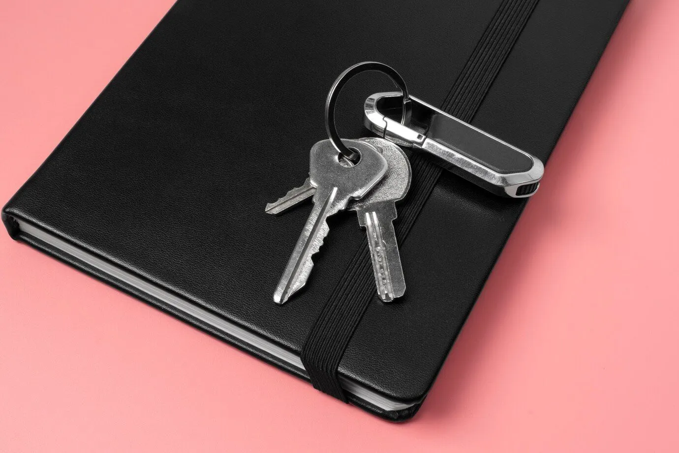 A set of keys with a fob resting on a black notebook