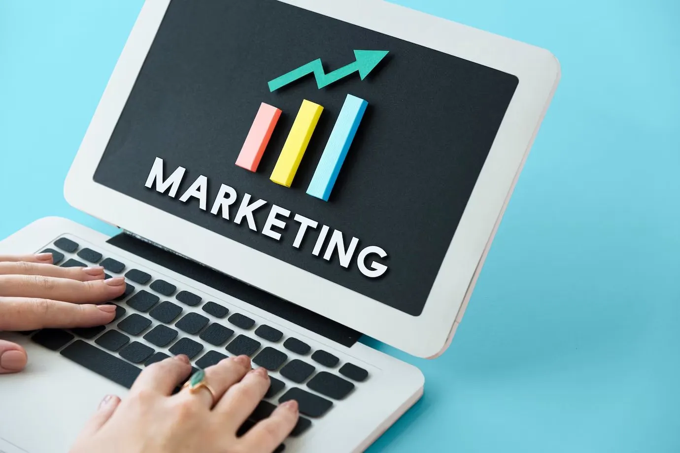 A laptop screen showing the word marketing above a rising bar chart