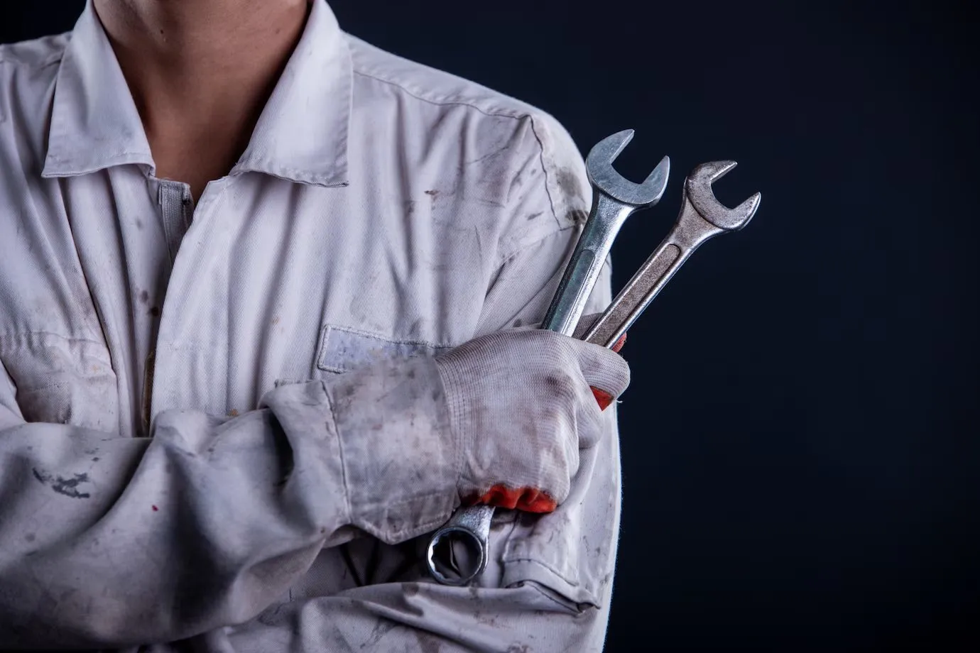 A maintenance worker in overalls holding a large spanner