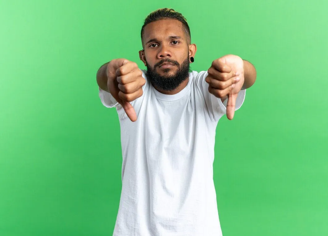 A man in a white t-shirt giving two thumbs down