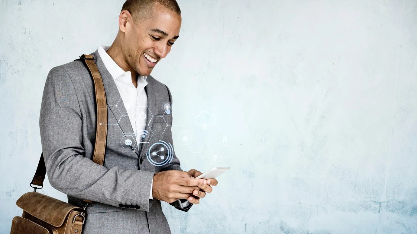A man with a satchel smiling as he looks at his phone