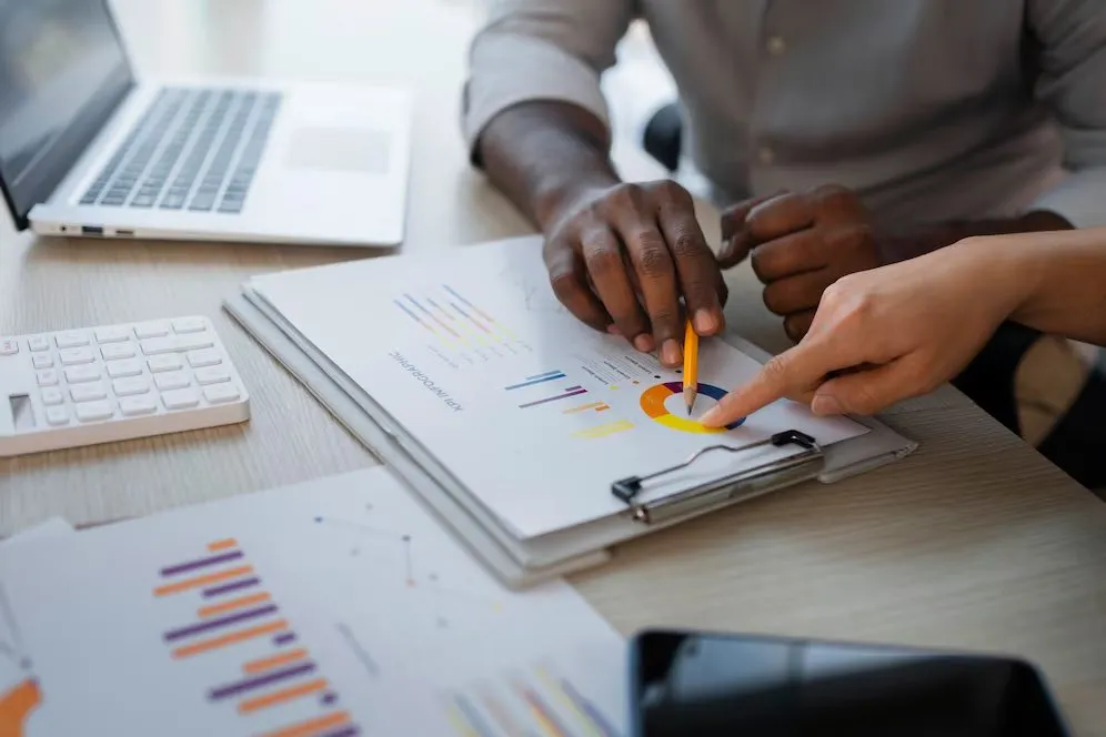 Two people marking up printed charts on a desk