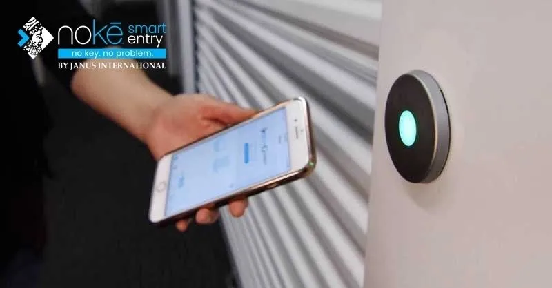 A phone unlocking a Nokē Smart Entry Bluetooth reader mounted beside a storage door