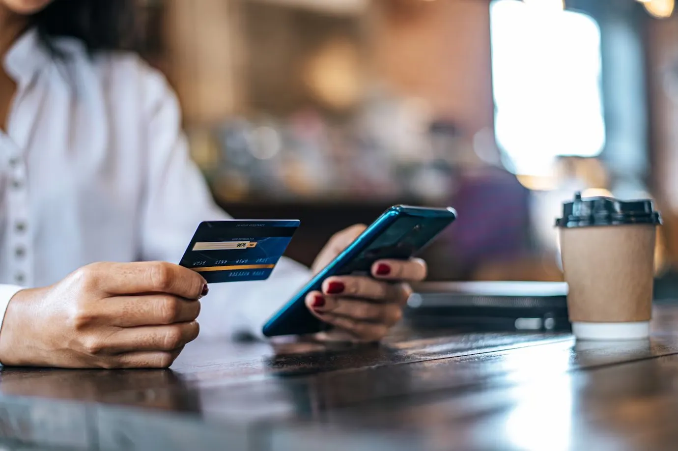 A woman holding a bank card while using her phone