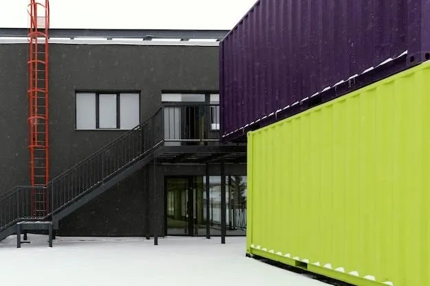 Purple and green shipping containers stacked beside a dark industrial building
