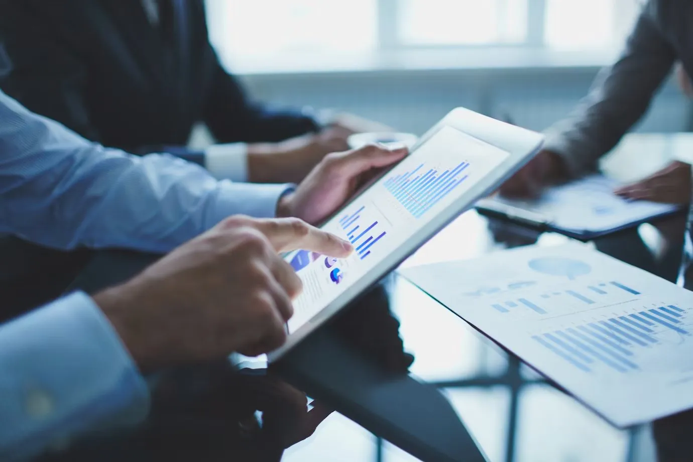 People in a meeting reviewing performance charts on a tablet