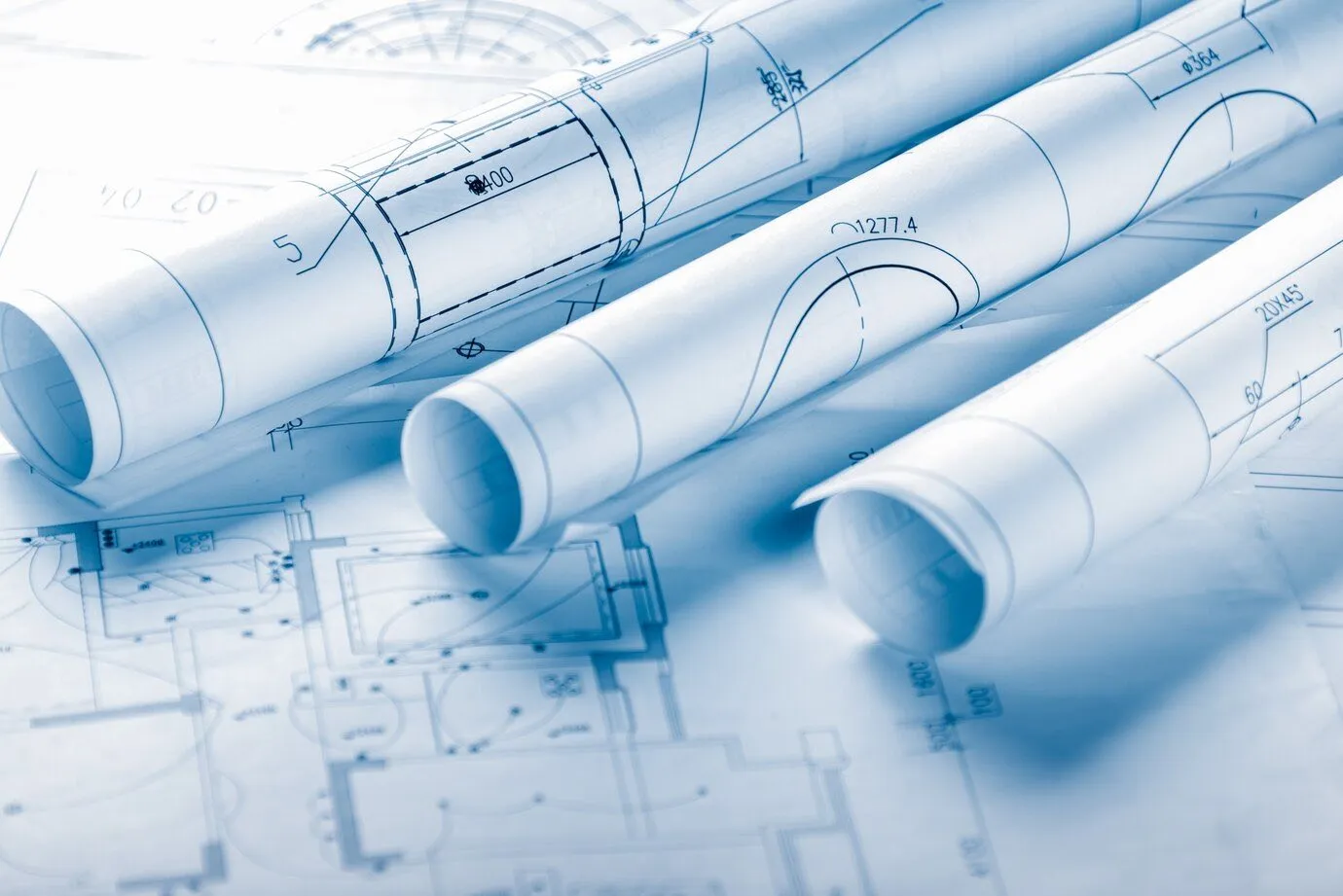 Rolled architectural blueprints laid across a technical site drawing