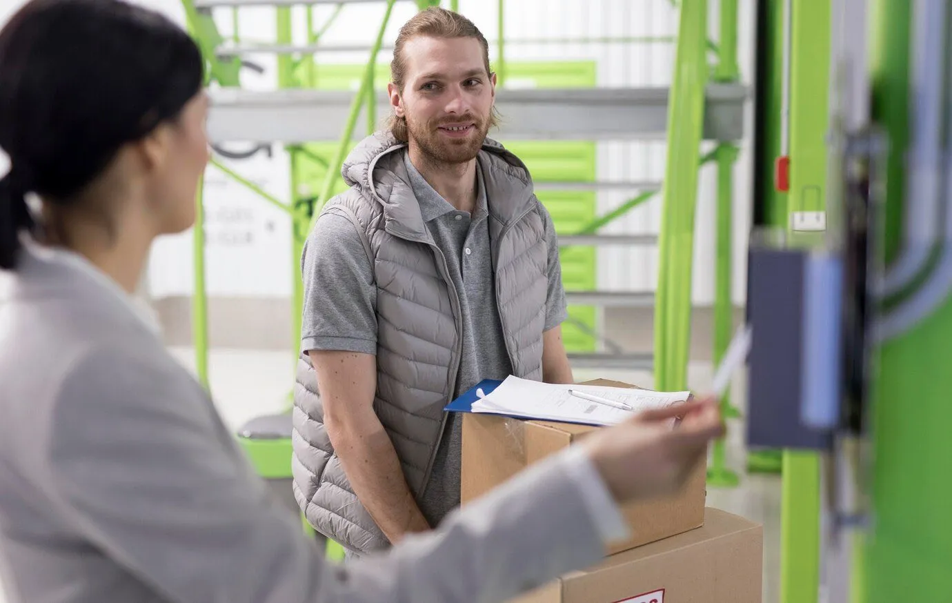 A staff member talking with a customer holding boxes in a storage facility