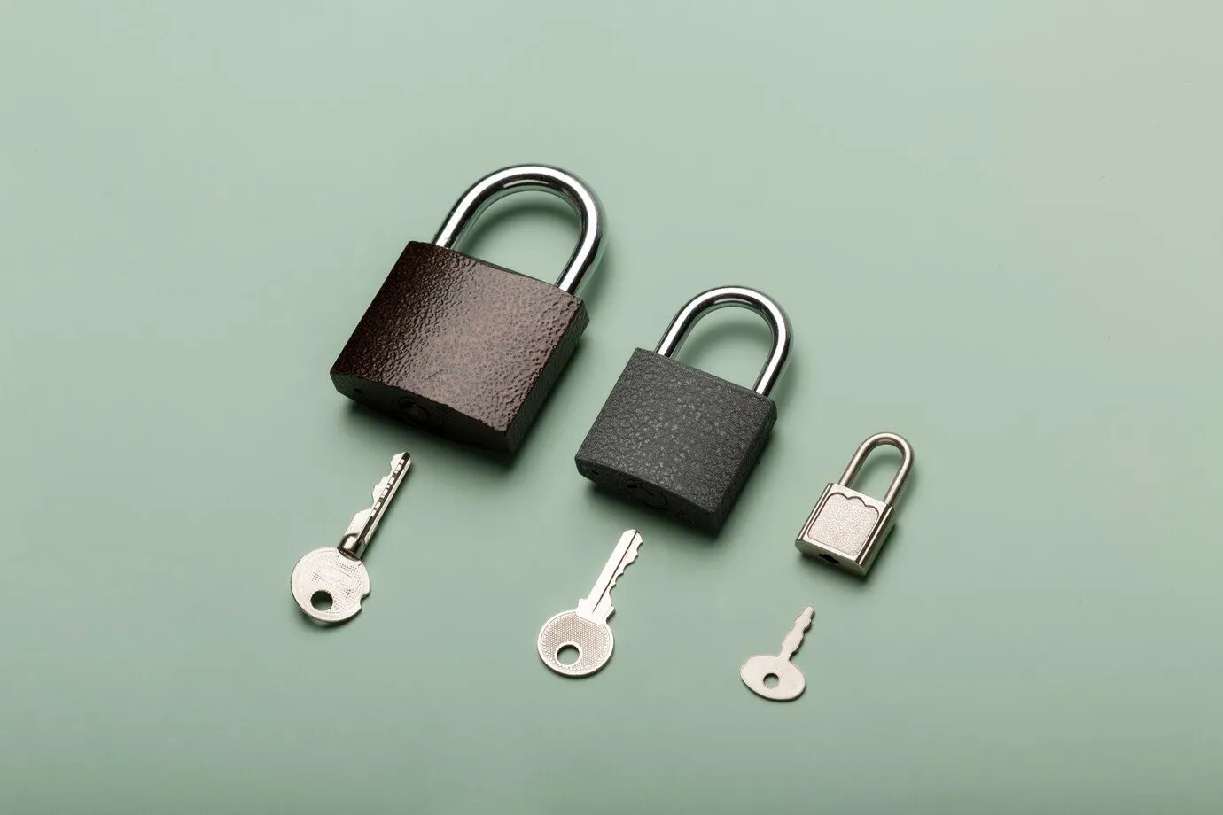 Three padlocks of different sizes laid out with their keys