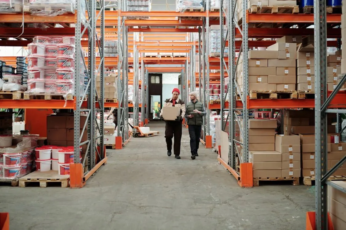 Two staff members walking between racked shelving in a storage warehouse