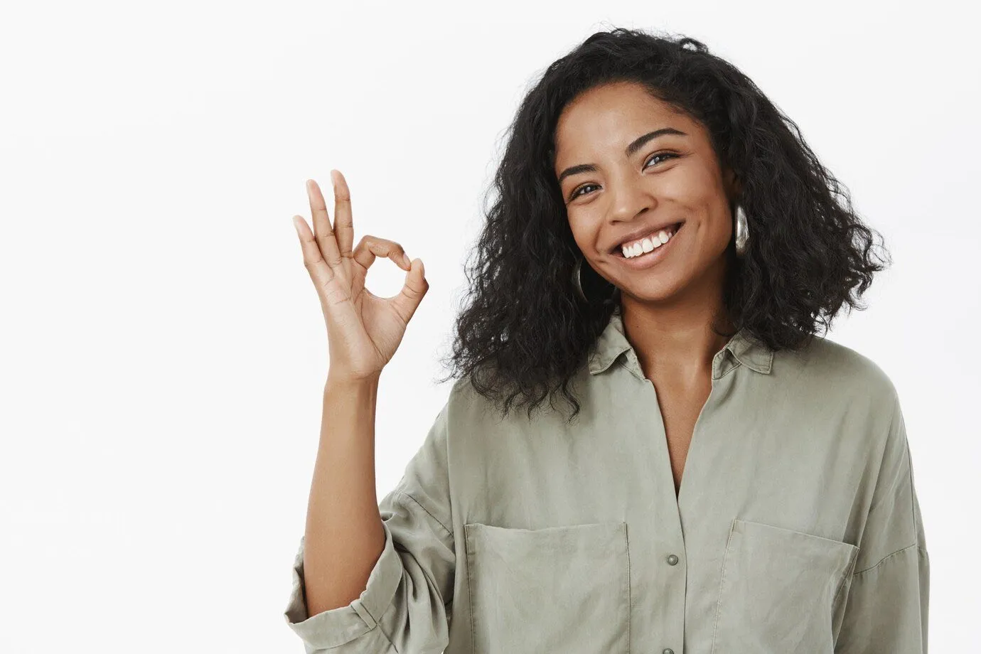A woman smiling and making an OK gesture with her hand