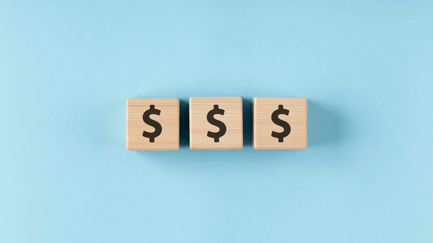 Three wooden blocks each showing a dollar sign