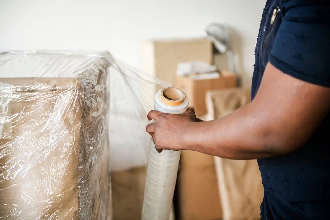 A person wrapping stored furniture in protective stretch film